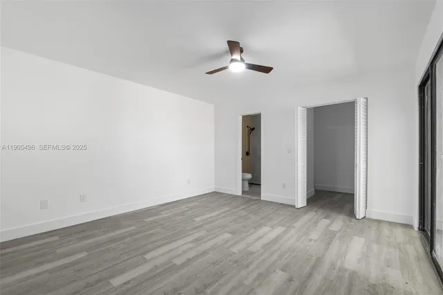 an empty room with wooden floor ceiling fan and windows