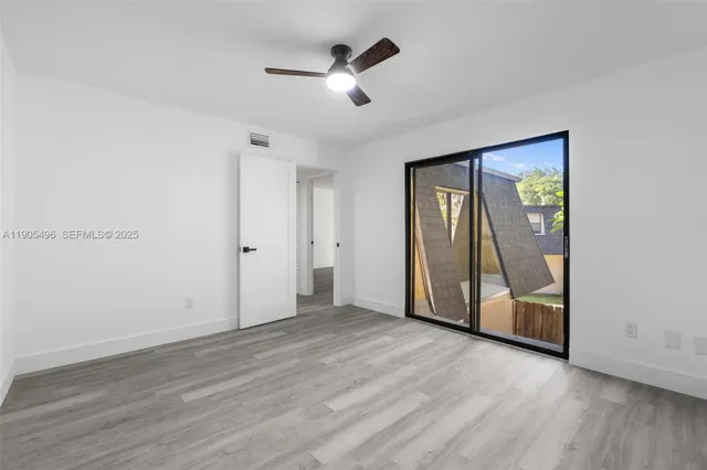 an empty room with wooden floor and a ceiling fan