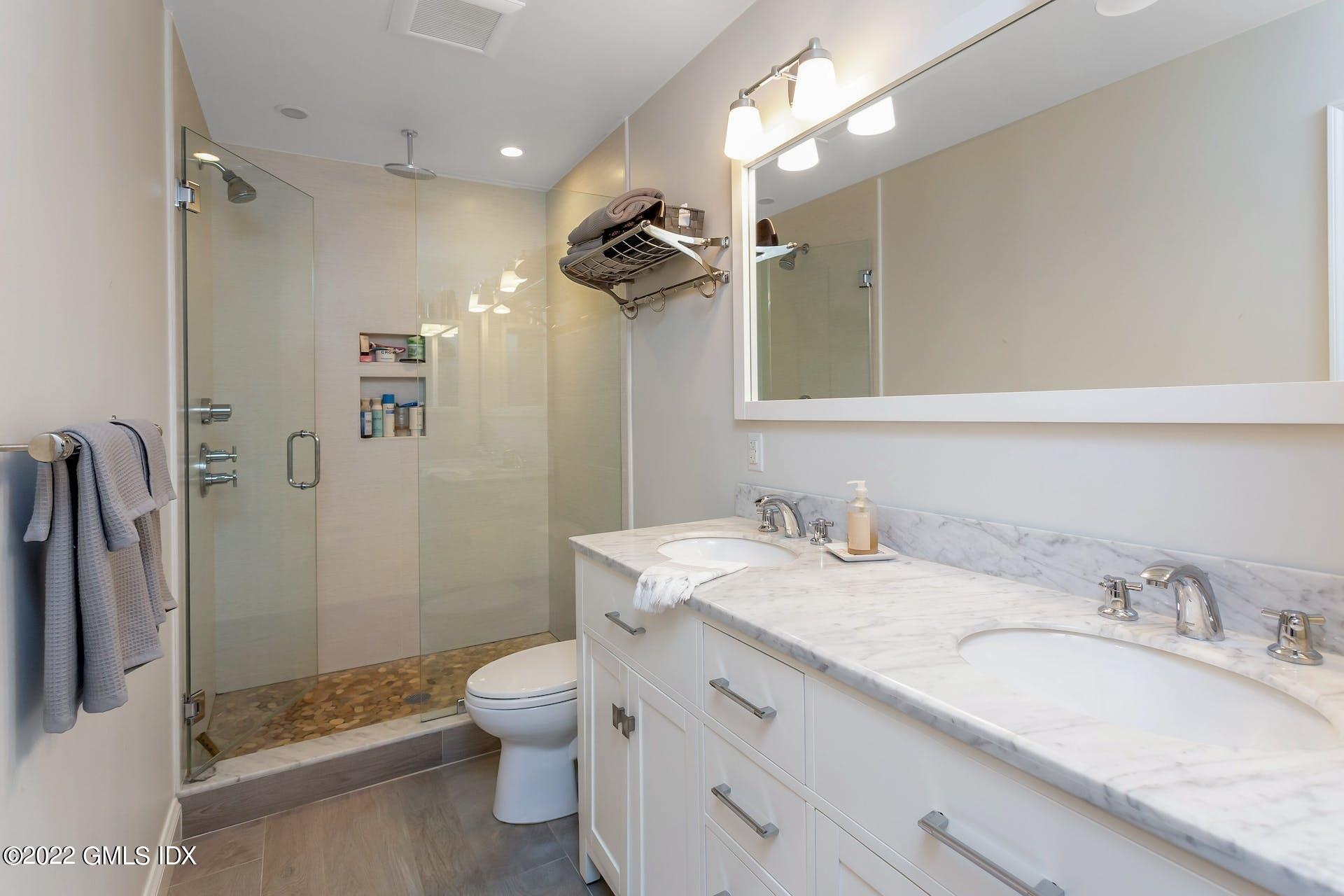 100 Silo Circle, Unit 100 Riverside, CT 06878 - Photo 7 of 22 a bathroom with a granite countertop sink a toilet a mirror and shower