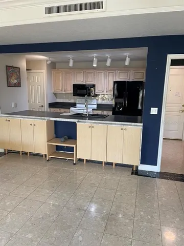a large white kitchen with stainless steel appliances granite countertop a stove and a sink