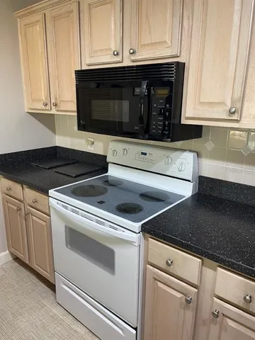 a kitchen with granite countertop white cabinets and black appliances