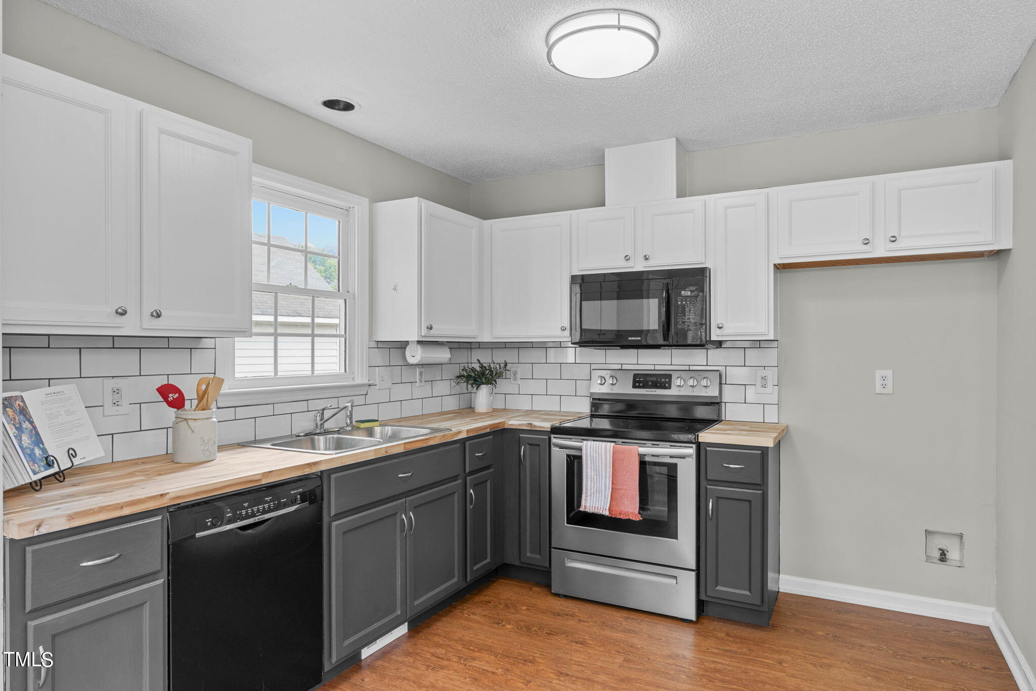 Undisclosed Address Garner, NC 27529 - Photo 12 of 31 a kitchen with stainless steel appliances granite countertop a sink dishwasher stove and white cabinets with wooden floor