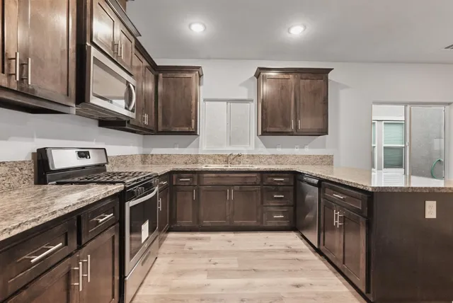 a kitchen with stainless steel appliances granite countertop wooden cabinets a stove top oven and granite counter tops
