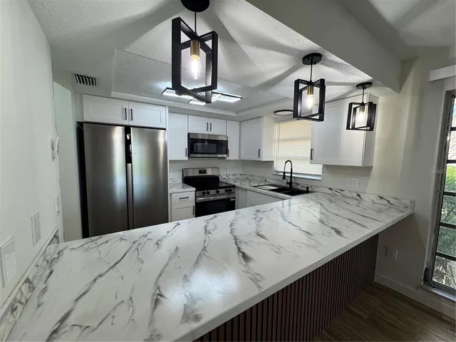 a kitchen with stainless steel appliances kitchen island a refrigerator and a sink