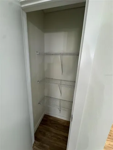 a walk in closet with wooden floor