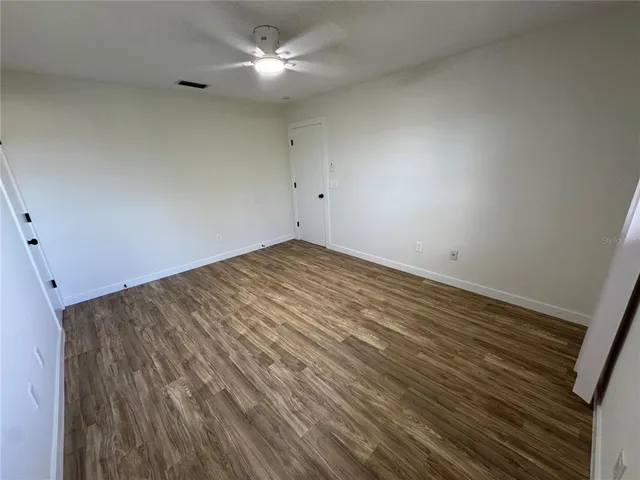 en empty room with wooden floor and ceiling fan
