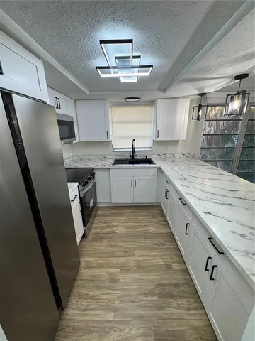 a large kitchen with stainless steel appliances granite countertop a sink stove and refrigerator