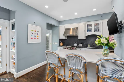 a kitchen with stainless steel appliances a microwave a stove a refrigerator a microwave a dining table and chairs with wooden floor