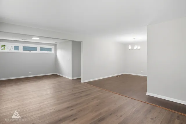 a view of an empty room with wooden floor and closet
