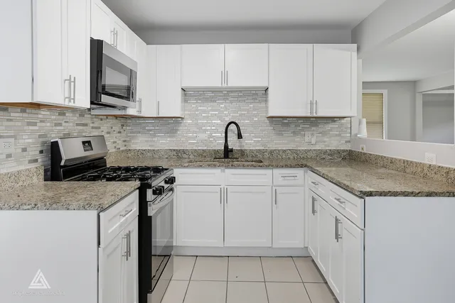 a kitchen with granite countertop white cabinets and white appliances