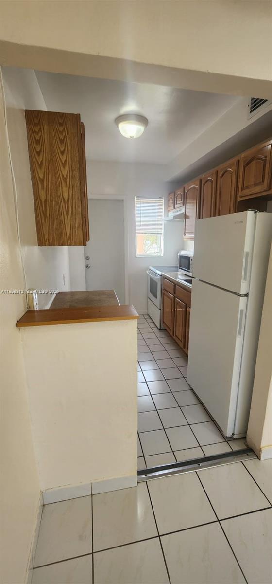 3670 Southwest 10th Street, Unit 10B Miami, FL 33135 - Photo 4 of 12 a kitchen with a refrigerator and a stove top oven