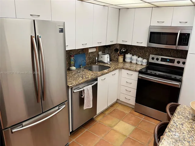 a kitchen with granite countertop a refrigerator stove and microwave