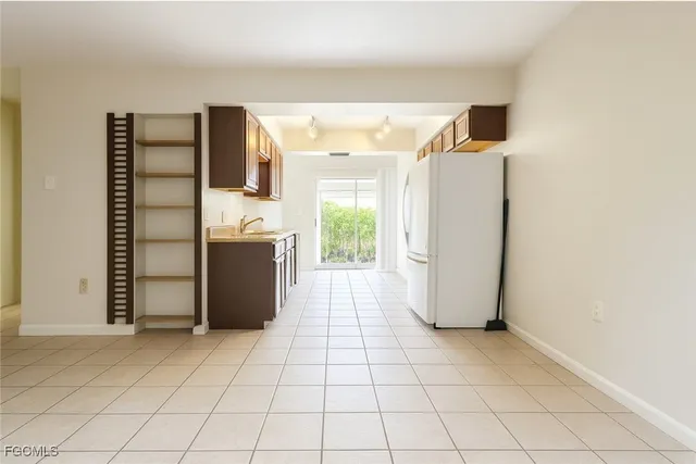 a view of a refrigerator in kitchen and an empty room