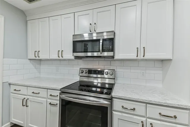 a kitchen with granite countertop white cabinets and stainless steel appliances