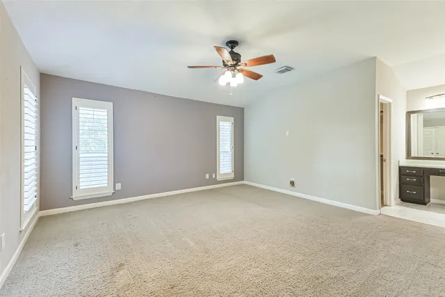 an empty room with windows and fan