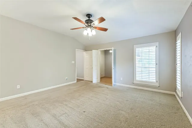 a view of an empty room with window and chandelier fan