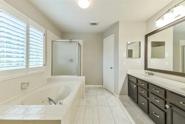 a spacious bathroom with a tub sink and mirror