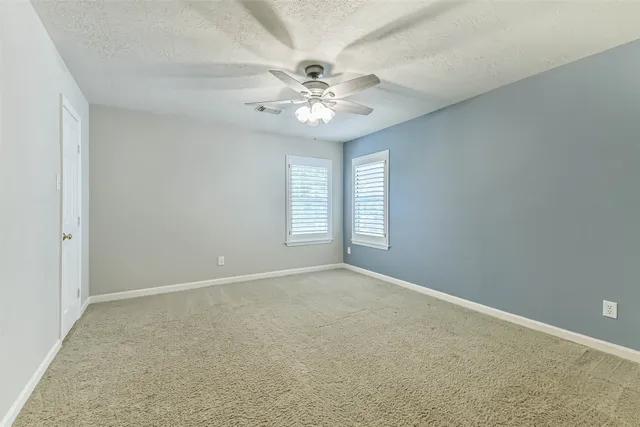 an empty room with windows and fan