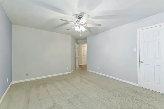 a view of an empty room with chandelier fan
