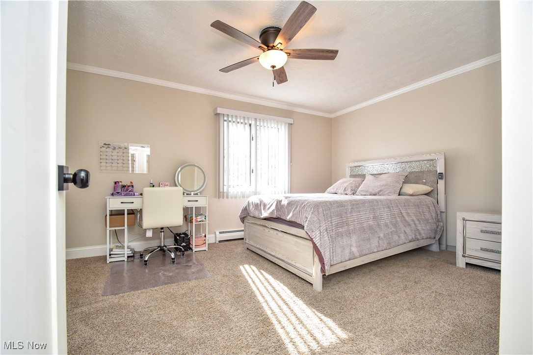 631 Carson Salt Springs Road Warren, OH 44481 - Photo 30 of 39 Carpeted bedroom with ceiling fan, a textured ceiling, ornamental molding, and a baseboard radiator