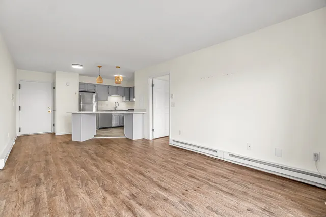 a view of kitchen and empty room with wooden floor