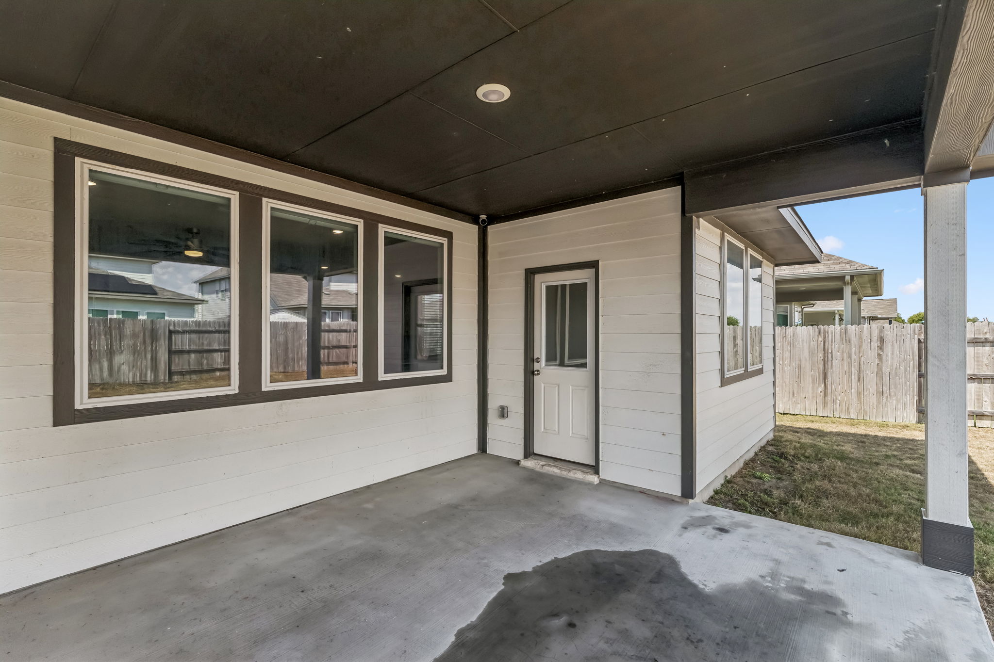 4009 Milano River Road Hutto, TX 78634 - Photo 38 of 40 A covered concrete patio provides sheltered outdoor space alongside the grass yard and wooden privacy fence.
