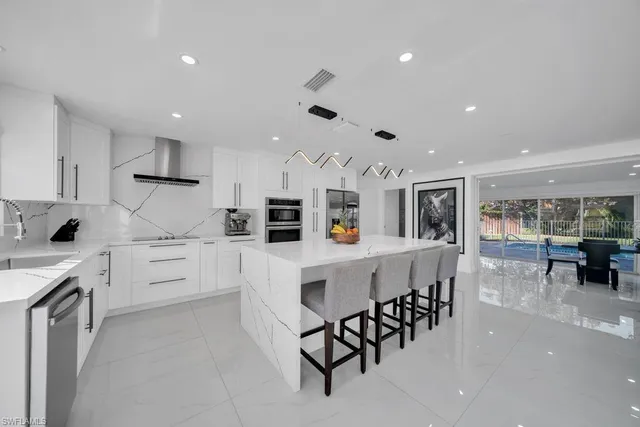 a kitchen with white cabinets and chairs