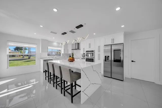 a kitchen with stainless steel appliances kitchen island granite countertop a sink a stove a refrigerator and cabinets