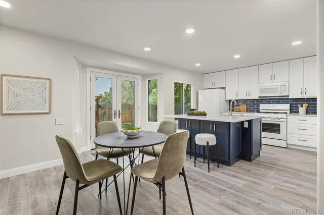 a kitchen with a dining table chairs and wooden floor