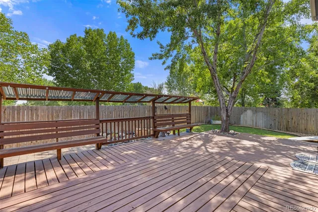 a view of a bench with wooden floor and fence