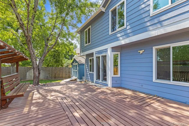 a view of backyard with large trees and wooden fence