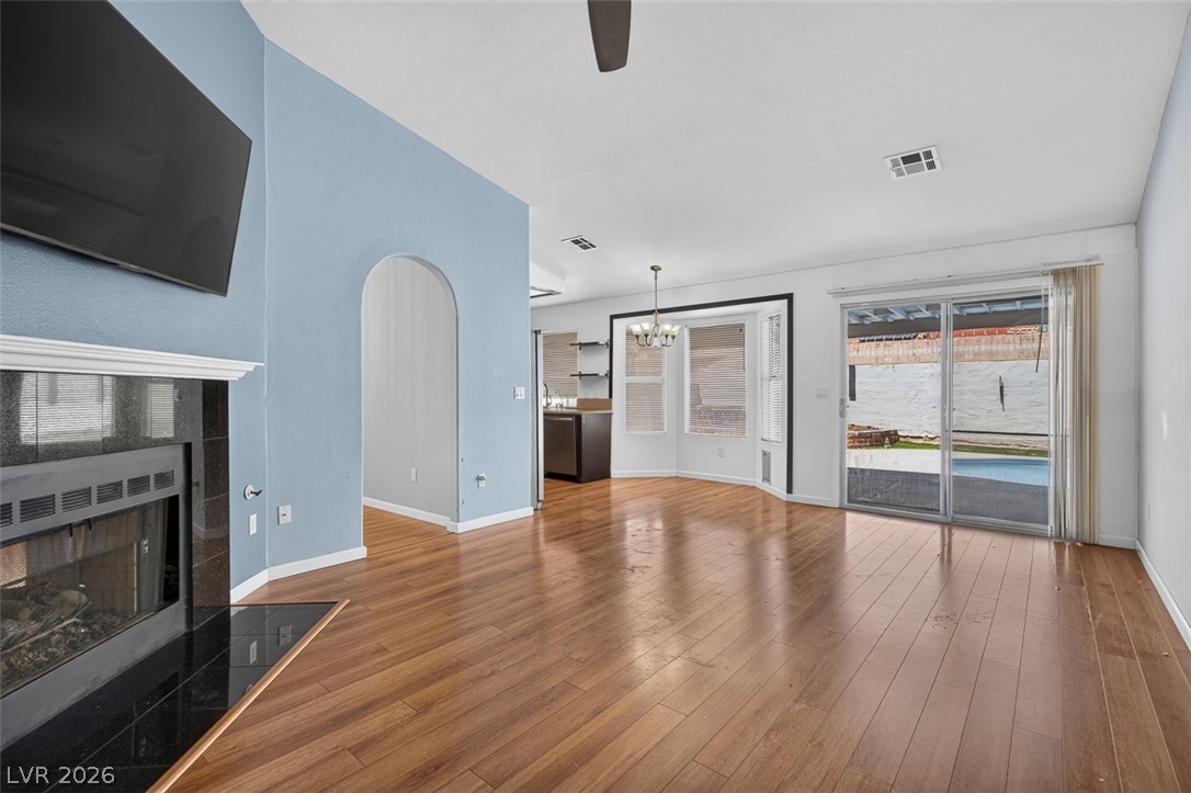 2609 Shakespeare Road Las Vegas, NV 89108 - Photo 12 of 41 Luminous family room boasts a sleek fireplace, gleaming hardwood floors, and sliding glass doors to outdoor leisure.