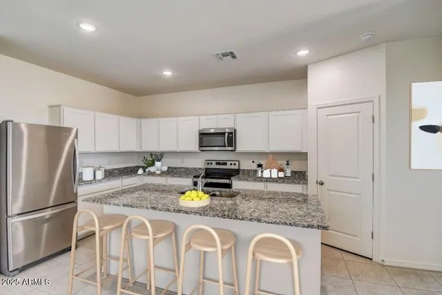 a kitchen with stainless steel appliances granite countertop a refrigerator a stove and a sink