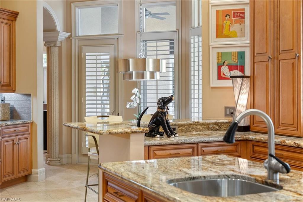 550 21st Avenue South Naples, FL 34102 - Photo 16 of 44 Kitchen with decorative columns, brown cabinetry, light stone countertops, and a sink