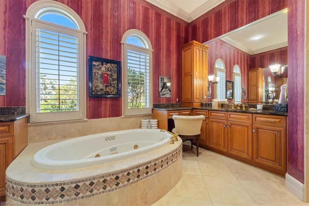 550 21st Avenue South Naples, FL 34102 - Photo 26 of 44 Bathroom featuring a jetted tub, vanity, ornamental molding, and a healthy amount of sunlight