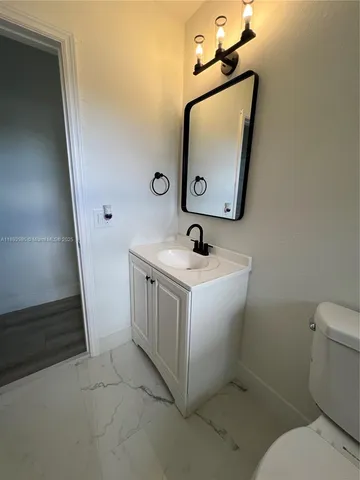 a utility room with a toilet a sink a vanity and mirror