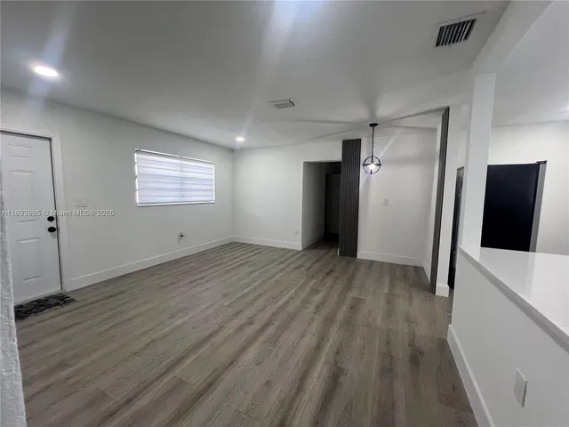 an empty room with wooden floor and mirror
