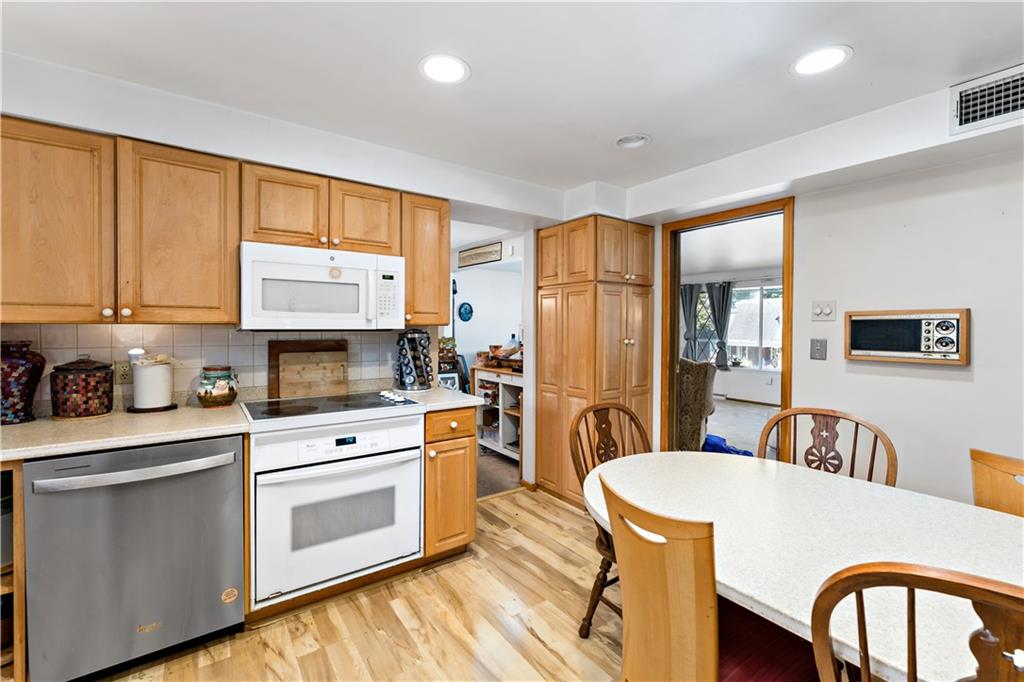 38 May Avenue McKees Rocks, PA 15136 - Photo 10 of 38 a kitchen with stainless steel appliances a stove a sink a refrigerator white cabinets a dining table and chairs with wooden floor