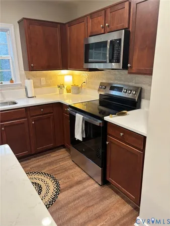 a kitchen with stainless steel appliances granite countertop wooden cabinets a stove top oven a sink and dishwasher