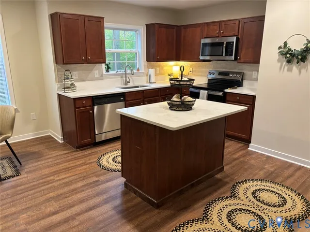 a kitchen with stainless steel appliances granite countertop a sink a stove a microwave and wooden cabinets