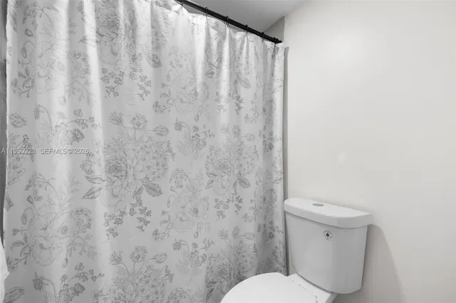 a white toilet sitting next to a shower curtain
