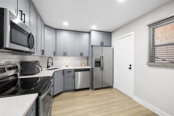 a kitchen with stainless steel appliances a stove a sink a refrigerator a microwave and cabinets