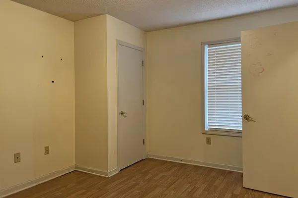 a view of an empty room with wooden floor and a window