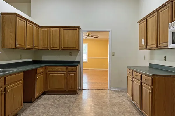 a kitchen with granite countertop a refrigerator a stove top oven and cabinets