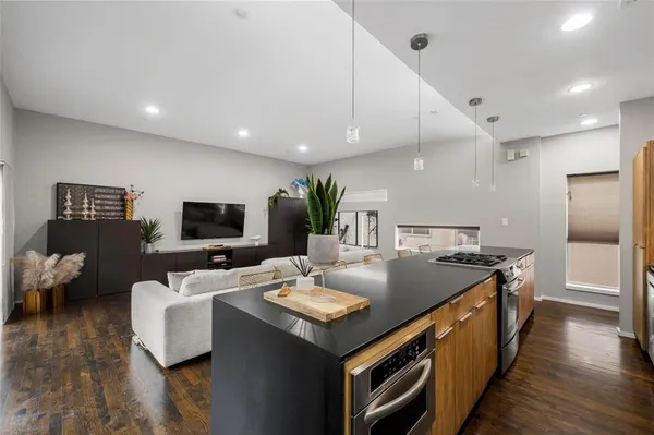 a living room with stainless steel appliances kitchen island granite countertop a sink a counter space and wooden floor
