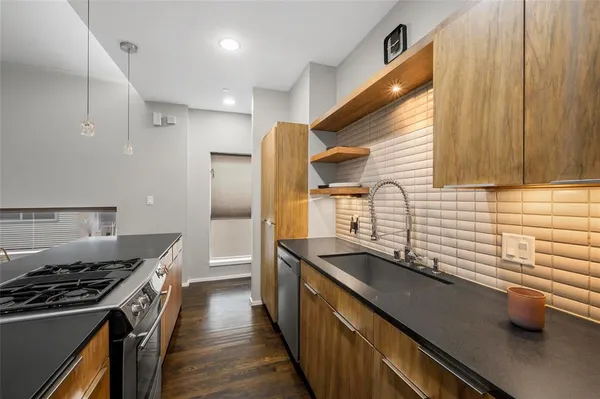 a kitchen with stainless steel appliances a sink dishwasher a stove and a refrigerator