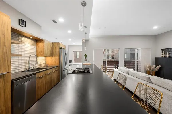 a large living room with stainless steel appliances granite countertop lots of counter space wooden floor and a window