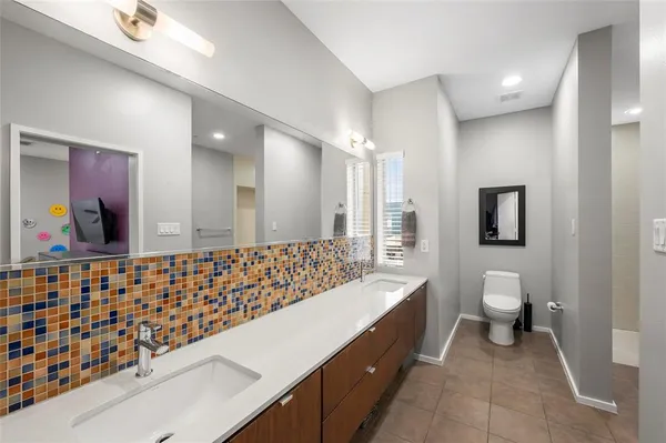a bathroom with a double vanity sink toilet and a mirror