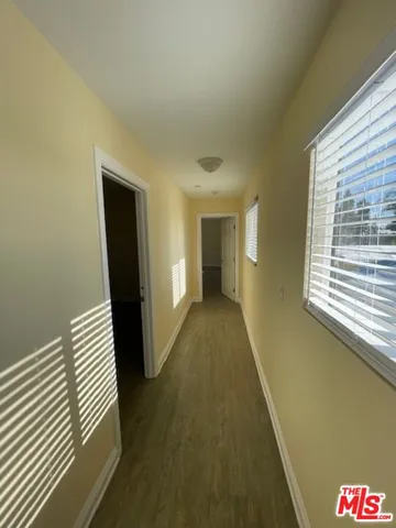 a view of hallway with wooden floor and cabinet