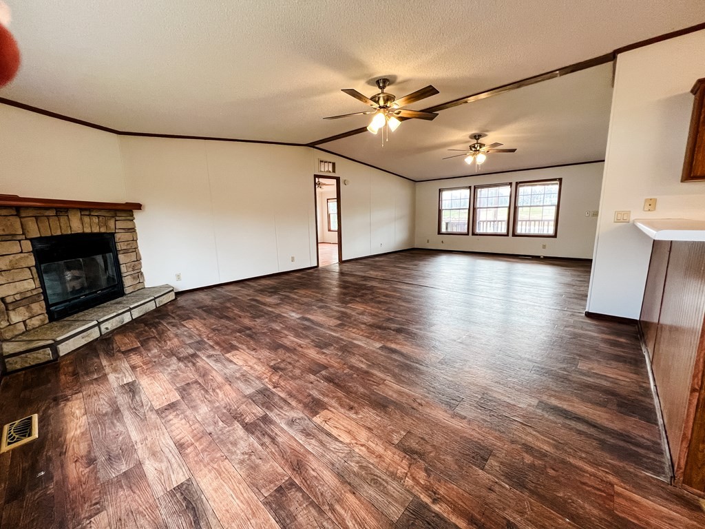725 Hulon Ferrell Road Baxter, TN 38544 - Photo 4 of 31 an empty room with wooden floor fireplace and windows